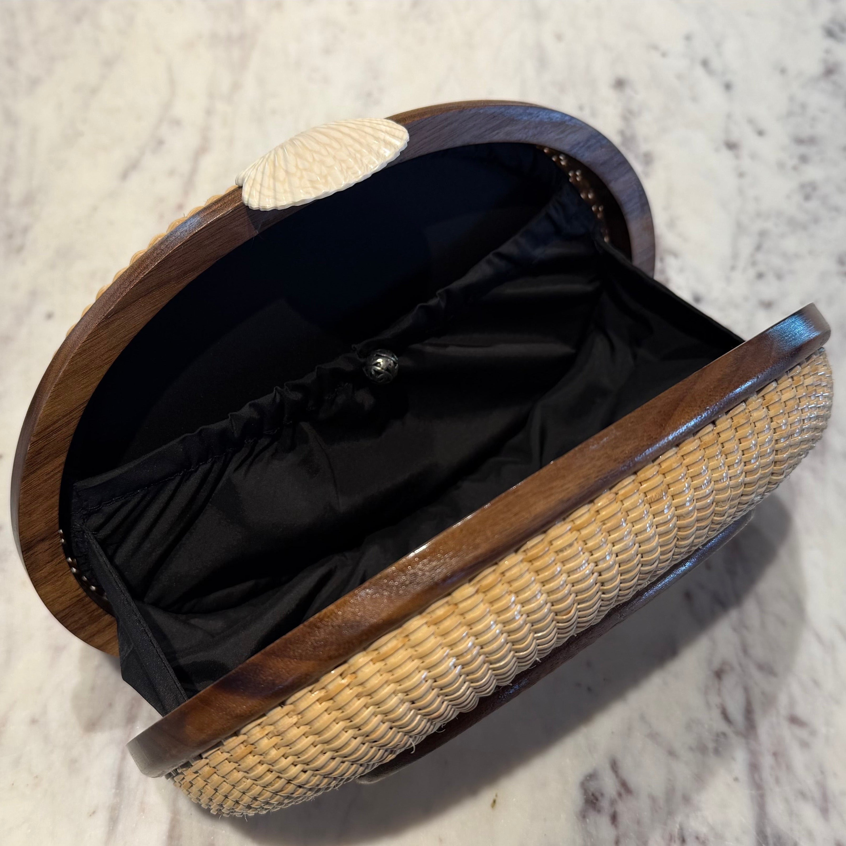 Open woven basket with black interior on a marble surface