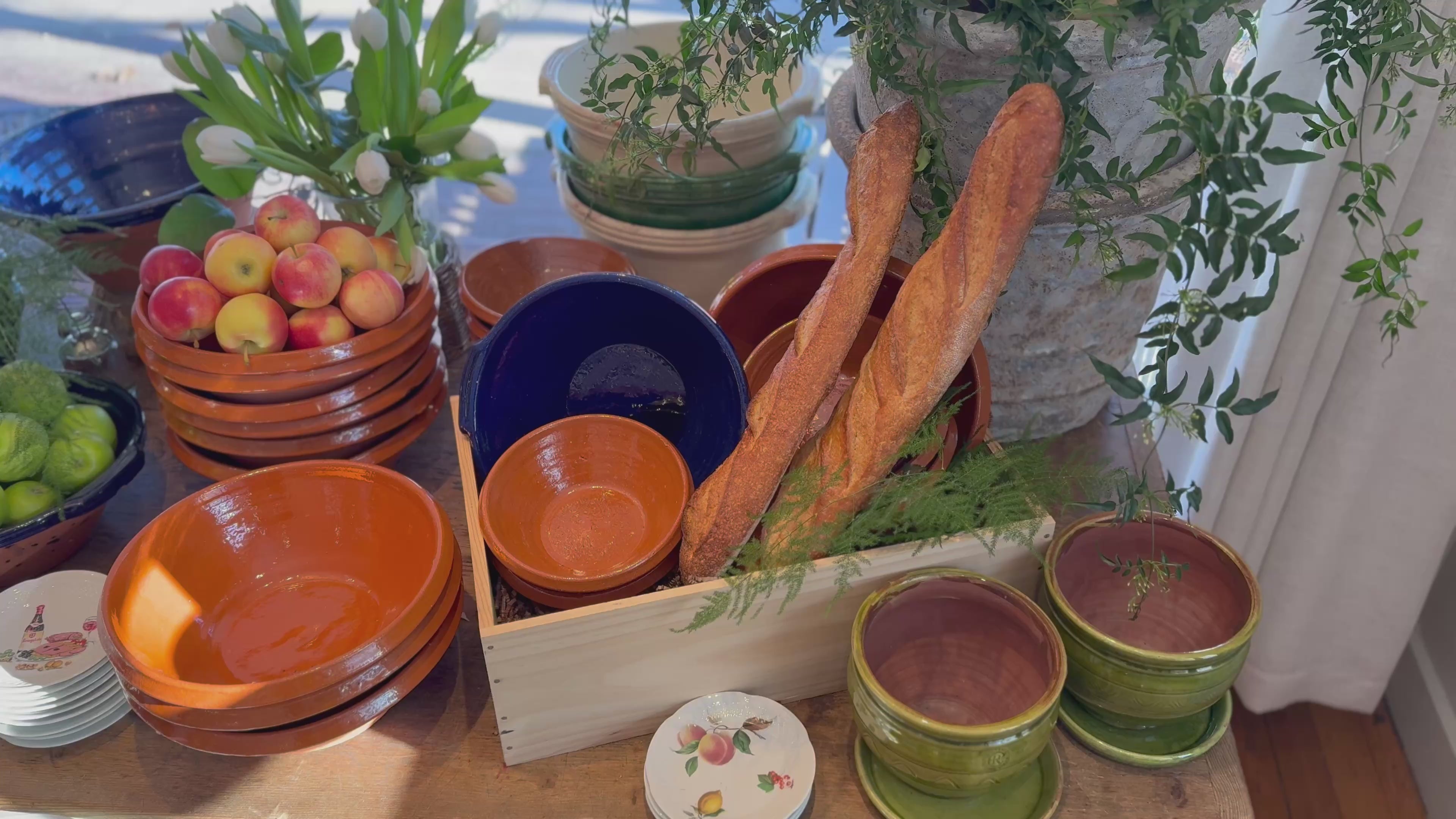 Load video: Panning view of a display table in the shop merchandised with bowls, plates, and other products and decor
